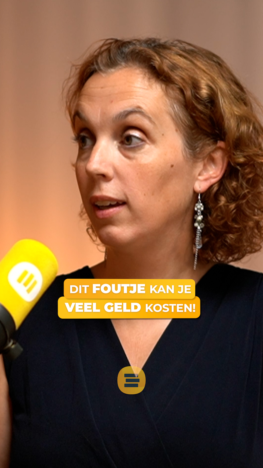 Vrouw met krullend haar spreekt in een microfoon met geel logo, met de tekst “Dit foutje kan je veel geld kosten!” in beeld.