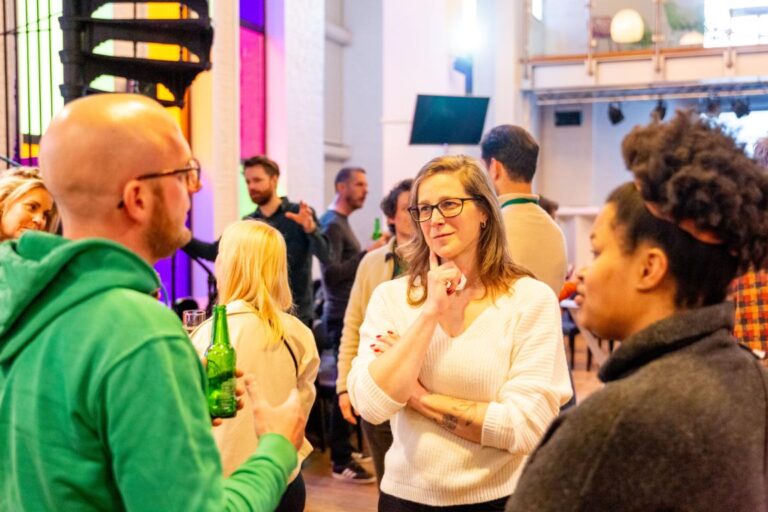 Bezoekers van het All Ears Club-evenement op 17 april 2024 in gesprek tijdens een informele netwerkbijeenkomst.