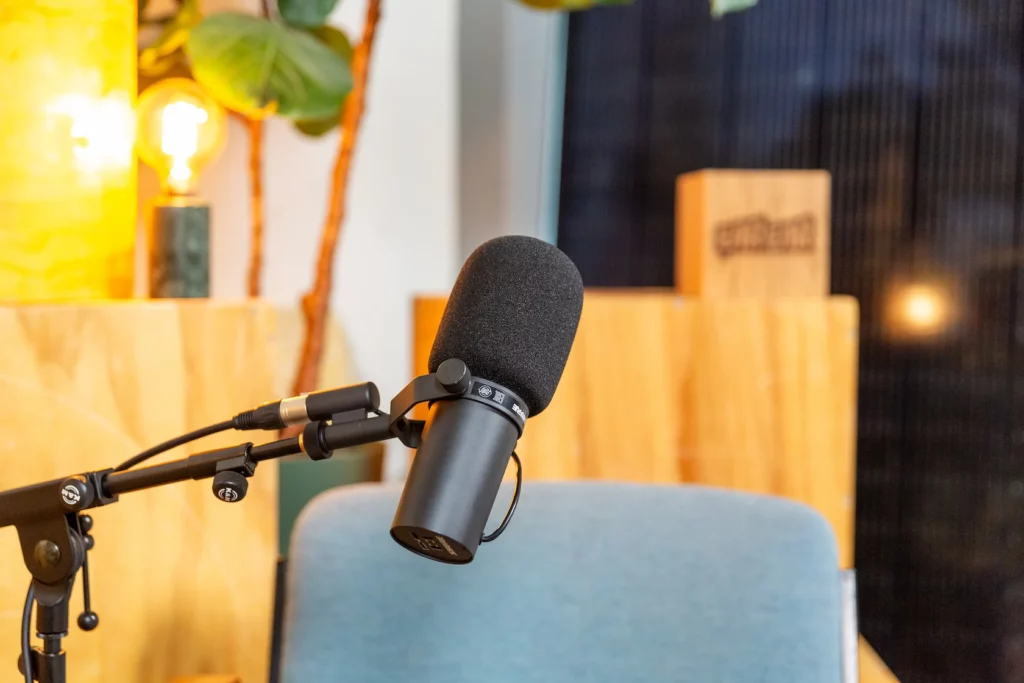 Zwarte podcastmicrofoon op een verstelbare arm voor een stoel in een warme, sfeervolle studio.