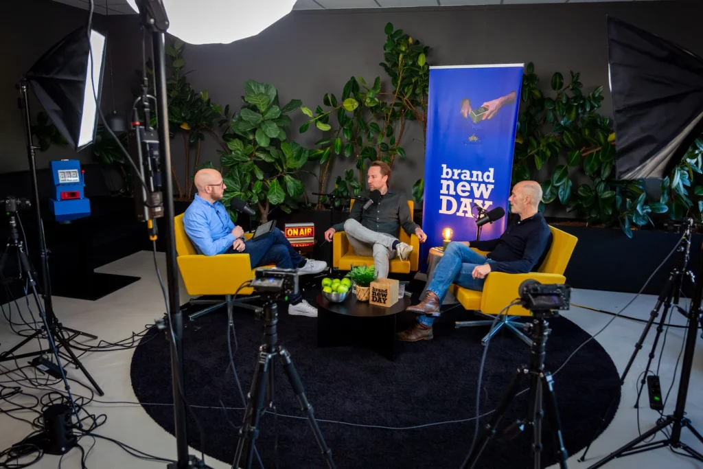 Drie mannen zitten in gele stoelen in een professioneel ingerichte podcaststudio voor een brainstormsessie van de podcast EarEar.