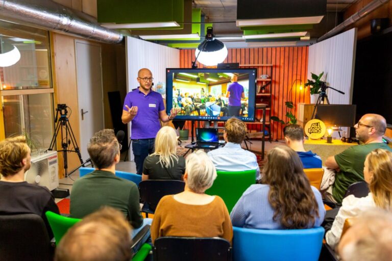 Spreker Lars Lensink geeft een presentatie aan een groep luisteraars tijdens een All Ears Club-bijeenkomst.