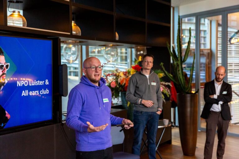 Man in paarse hoodie geeft presentatie tijdens het All Ears Club evenement bij NPO Luister.