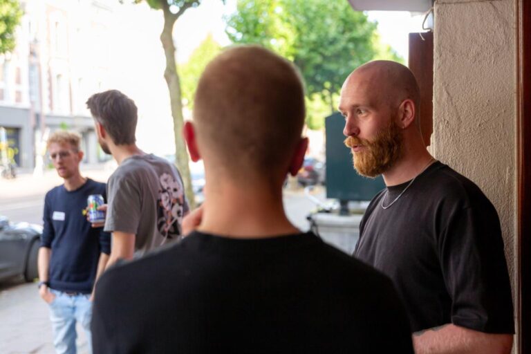 Vier mannen staan buiten in gesprek tijdens All Ears Club bij De Stroom op 25 juli.