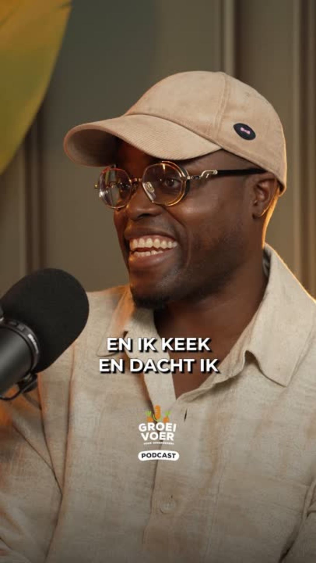 Man met bril en beige pet spreekt lachend in een microfoon tijdens de Groeivoer podcast.